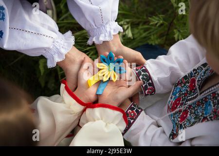 Les mains des enfants et des adultes dans les chemises brodées soigneusement dans l'unité tiennent le symbole bleu-jaune trident de l'Ukraine . Tenez-vous avec l'Ukraine. Patriots, nationa Banque D'Images