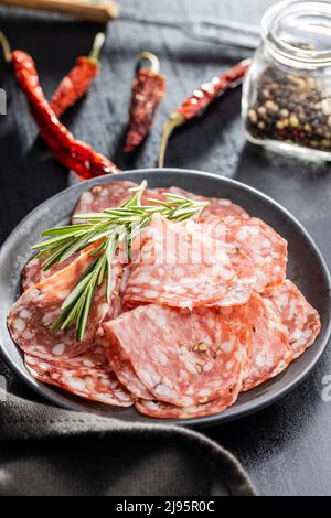 Émincé de saucisse italienne de salami avec du poivre sur une assiette. Banque D'Images