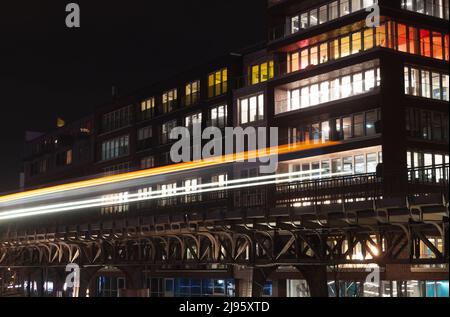 Vue nocturne sur la ville avec fenêtres éclairées de la maison résidentielle moderne et des sentiers lumineux avec phares flous Banque D'Images