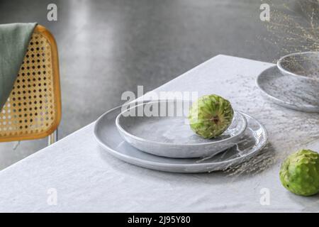 Table élégante avec fruits de cherimoya sur la nappe en lin. Table extérieure pour les vacances d'été. Banque D'Images