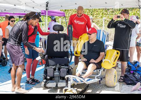 Miami Beach Florida, Sabrina Cohen Adaptive Beach Day, handicapés besoins spéciaux roues d'eau handicapées fauteuil roulant flottant, Black man mâle volontaire volun Banque D'Images