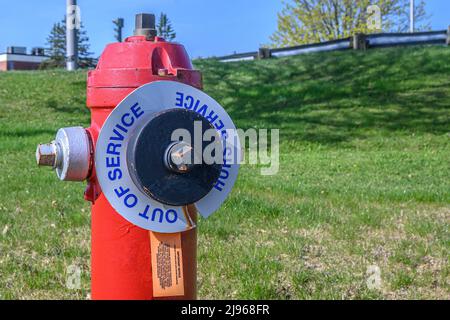 Une borne incendie rouge hors service. La plus grande couverture est peinte en noir et comporte un panneau indiquant « HORS SERVICE ». Espace pour le texte. Banque D'Images