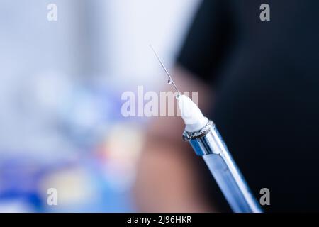 Les mains du dentiste préparent la seringue pour donner l'anesthésie dentaire à son patient. Mise au point sélective. Banque D'Images