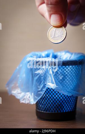 Un homme jette une pièce d'un euro dans un poubelle, une balle verticale Banque D'Images
