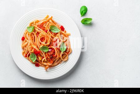 Une portion de pâtes linguini à la sauce tomate et au basilic sur fond gris avec un espace de copie. Banque D'Images