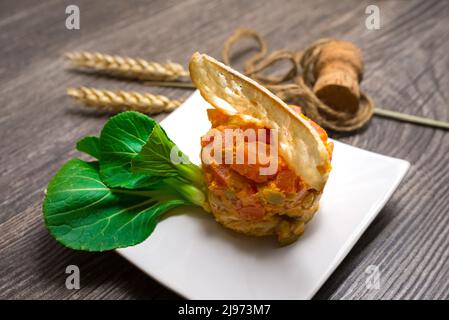 Escalope de poulet avec tomate épicée et relish aux olives. Décoration avec tranche mince de crouton, jeune pak choi frais. Anneau à salade utilisé pour former un plat. Banque D'Images