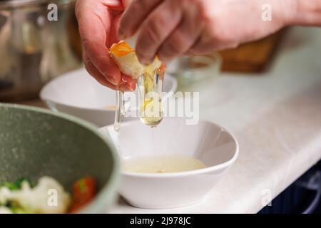 femme caucasienne sérante mains cassant blanc oeuf de poulet au-dessus du bol blanc Banque D'Images