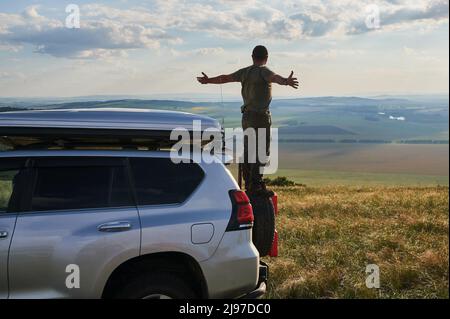 Jeune homme jouissant d'une nuit de lune sur le haut de son camping-van Banque D'Images