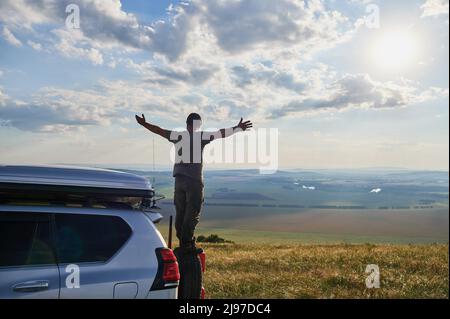 Jeune homme jouissant d'une nuit de lune sur le haut de son camping-van Banque D'Images