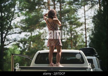 Jeune femme qui profite d'une nuit de lune au-dessus de sa camionnette de camping-car Banque D'Images