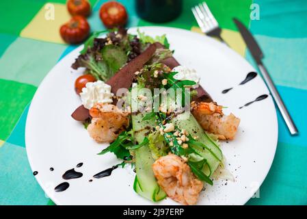 Salade verte à la poire (poire ivre, poire au vin) et crevettes à la sauce au yaourt, saupoudrées de pignons de pin Banque D'Images