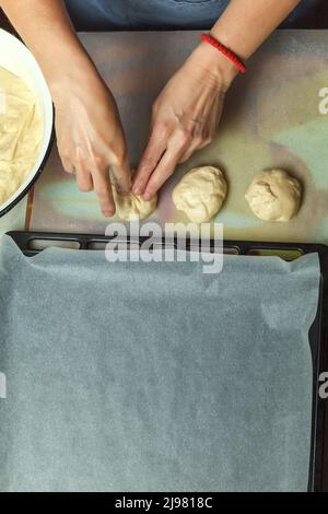 Le confiseur forme des petits pains avec des cerises à partir de la pâte à pâtisserie Banque D'Images