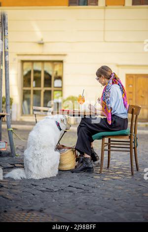 Femme mangeant des pâtes italiennes tout en étant assise avec un chien au restaurant dans la rue à Rome Banque D'Images