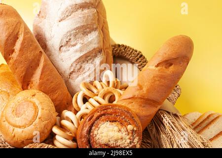 Pain avec petits pains, bagels de séchage, épis de blé sur fond jaune. Expérience culinaire. Banque D'Images