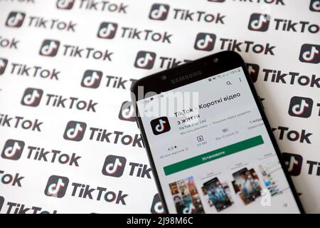 TERNOPIL, UKRAINE - 2 MAI 2022 : application pour smartphone Tik Tok à l'écran et nombreux logos TikTok imprimés sur papier. Tiktok ou Douyin est un célèbre short chinois Banque D'Images