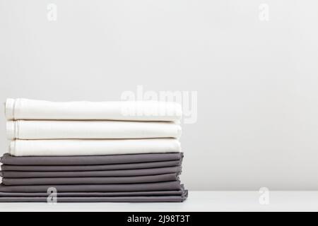 Une pile de draps gris et blancs, des draps sur la table. Banque D'Images