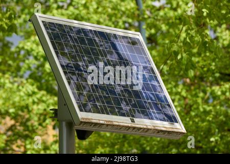 Gros plan d'un panneau solaire unique monté sur un support avec des arbres verts en arrière-plan Banque D'Images