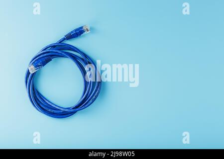 Bobine d'un câble réseau Internet pour la transmission de données sur fond bleu. Cordon de raccordement pour câble LAN. Banque D'Images