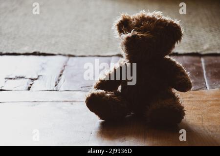 ours en peluche brun assis sur un vieux parquet dans une pièce sombre, jouet pour enfants sur le sol, peur Banque D'Images