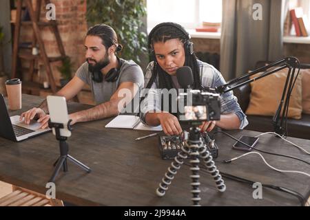 Plan horizontal de deux blogueurs modernes, hommes et femmes, travaillant ensemble sur un contenu intéressant pour les suiveurs Banque D'Images