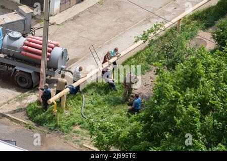 Tiraspol, Moldova - 17 mai 2022 : des travailleurs masculins ont fixé une rupture dans un tuyau d'alimentation en eau et d'assainissement. Accident sur la ligne de l'infrastructure urbaine. Mauvaise q Banque D'Images