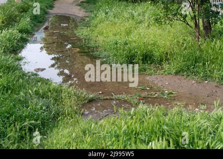 Égout de percée d'eau. Percée d'eau dans la conduite de chauffage, l'eau coule sous le couvercle d'égout sur la route Banque D'Images