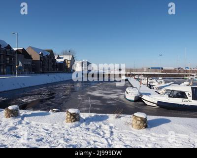 Hiver froid et lumineux jour avec de la neige sur le sol. Des feuilles de glace, flotteurs sur l'eau dans le port. Ben Wyvis en arrière-plan Banque D'Images