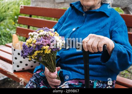 Personnes âgées dans les foyers de soins infirmiers, services de soins de longue durée dans les établissements résidentiels pour personnes âgées et adultes âgés. Seule femme âgée assise sur un banc à l'extérieur Banque D'Images