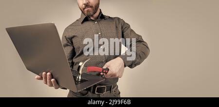 Homme non rasé coupe courte vue ordinateur portable frapper l'ordinateur avec fond gris marteau, dommages matériels Banque D'Images