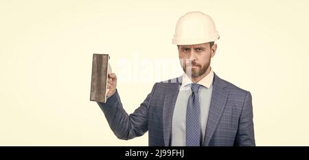 ingénieur en casque avec spatule. renouvellement et réparations. homme d'affaires confiant en costume, espace de copie Banque D'Images