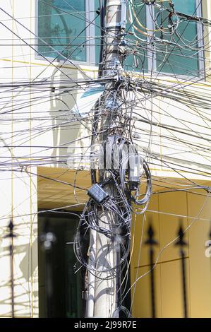 Câbles de communication Internet en fibre optique noirs désorganisés et enchevêtrés sur des poteaux en béton couramment trouvés dans les rues des grandes villes de Roumanie Banque D'Images