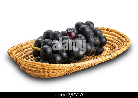 Bouquet de raisins noirs mûrs dans un plateau en bambou isolé sur fond blanc avec un chemin d'écrêtage. Banque D'Images