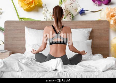 Belle jeune femme pratiquant le yoga dans la chambre, vue arrière Banque D'Images