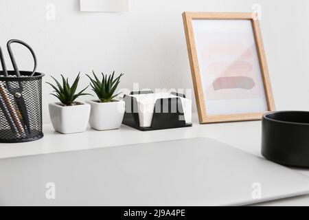 Support avec notes adhésives, plantes de maison et fournitures de papeterie sur table, gros plan Banque D'Images