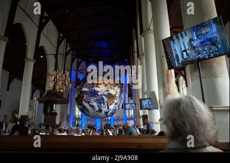 Une femme est vue assis dans l'église tout en regardant une grande boule de la Terre. Gaia est une œuvre d'art itinérante de l'artiste britannique Luke Jerram. Mesurant sept mètres de diamètre et créé à partir de 120dpi images détaillées de la surface de la Terre de la NASA, l'œuvre offre l'occasion de voir notre planète, flottant en trois dimensions. Cette expérience donne aux gens un sentiment d'admiration, une réalisation profonde de l'interconnexion de la vie sur Terre. Dans la mythologie grecque, Gaia est la personnification de la Terre mère. Cette œuvre appartient à Arcadia, un programme culturel de 100 jours qui se déroule cet été dans la province de Fries Banque D'Images