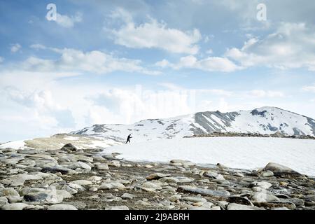 Homme avec sac à dos marchant sur la colline de neige dans les belles montagnes contre le ciel bleu à Almaty, Kazakhstan Banque D'Images