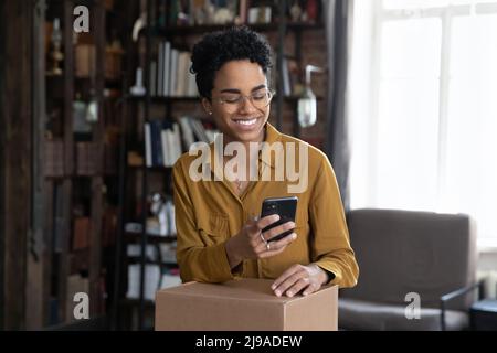 Femme tient le téléphone portable faire la commande de services de livraison pour l'envoi de boîte Banque D'Images