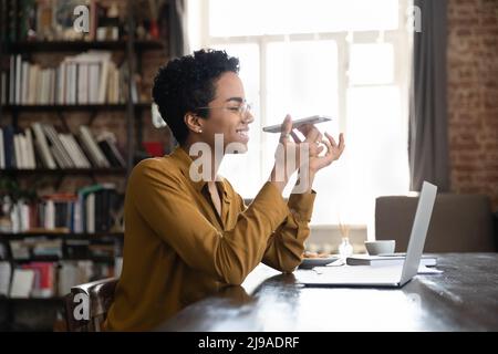 Une femme africaine tient son smartphone pour parler à l'aide d'un haut-parleur Banque D'Images