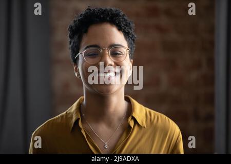 Femme africaine en lunettes ayant le sourire charmant pose pour l'appareil photo Banque D'Images