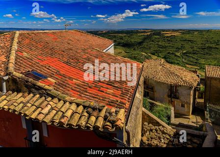 Vue aérienne des vieux toits de terre cuite et des champs en terrasse entourant une vallée par l'église forteresse Iglesia de Santa Maria à Ujue, Navarre, Espagne Banque D'Images