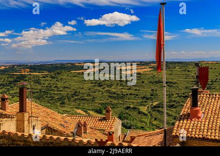 Vue aérienne des vieux toits de terre cuite et des champs en terrasse entourant une vallée par l'église forteresse Iglesia de Santa Maria à Ujue, Navarre, Espagne Banque D'Images