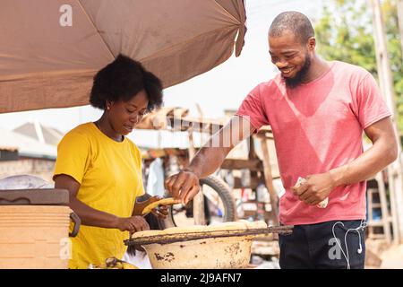 les gens qui achètent du plantain rôti auprès d'un vendeur de bord de route Banque D'Images