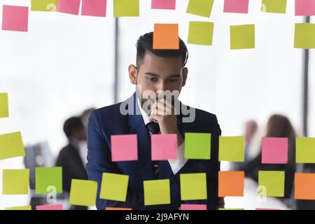 Un homme d'affaires indien attentif examine les notes écrites sur les autocollants post-it Banque D'Images
