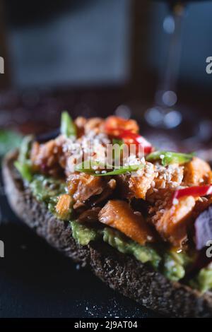 la personne mange un sandwich frais avec de l'avocat, du poisson frit au saumon rouge, de l'algue et du poivre Banque D'Images