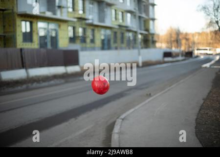 Un ballon rouge survole la route. L'objet est dans l'air. Contraste des couleurs. Forme et arrière-plan. Banque D'Images