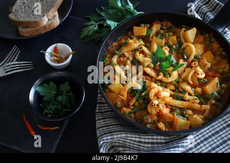 Des rondelles de calmar en purée avec des pois et des pommes de terre dans une casserole. Directement au-dessus. Banque D'Images