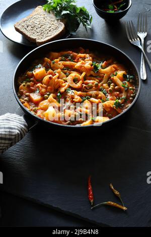 Des rondelles de calmar en purée avec des pois et des pommes de terre dans une casserole. Directement au-dessus. Banque D'Images