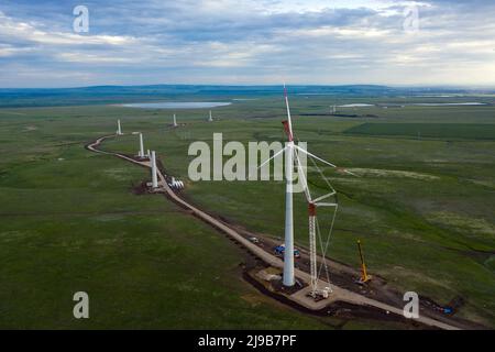 L'éolienne interprète au coucher du soleil. Installation des pales de rotor sur l'éolienne Banque D'Images