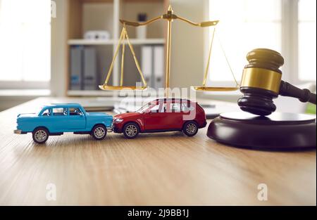 Gavel et deux voitures de jouets écrasées sur la table d'avocat ou de juge illustrant le concept d'assurance automobile Banque D'Images