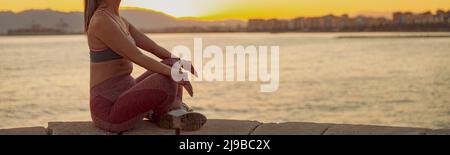 Asian sportswoman pratiquant le yoga, assis sur le bord de la mer Banque D'Images